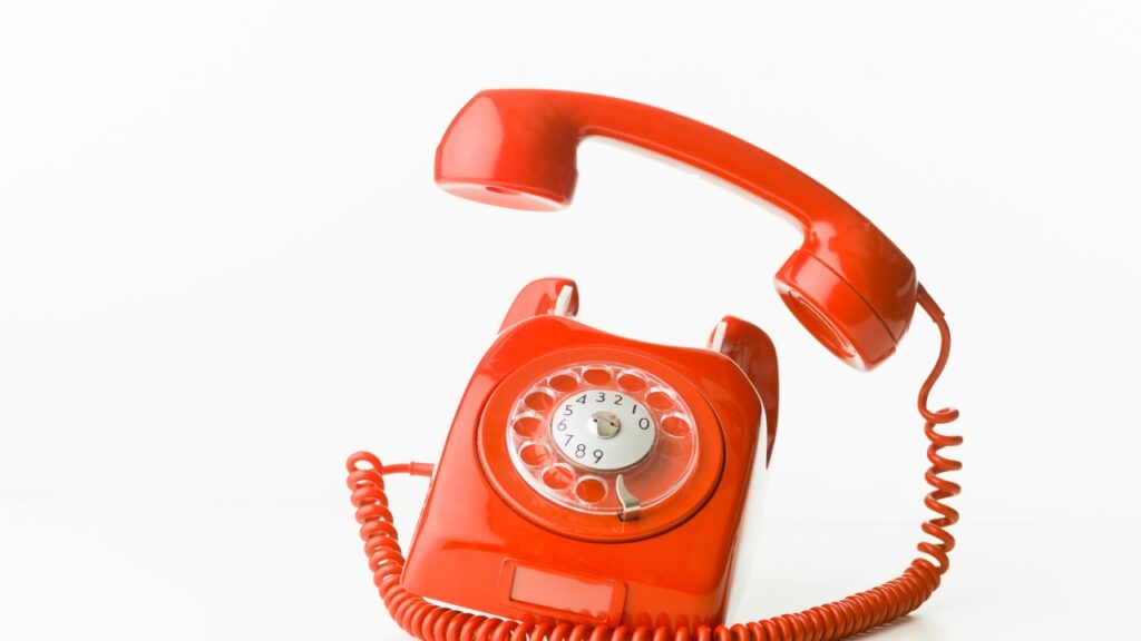 Red old fashion rotary phone with the phone handle off the phone