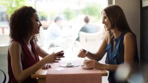 two women having a conversation at a table.